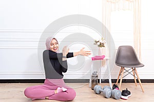 Healthy asian muslim woman stretching while doing exercise at home
