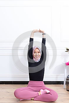 Healthy asian muslim woman stretching while doing exercise at home