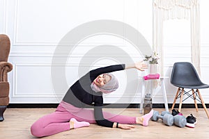 Healthy asian muslim woman stretching while doing exercise at home