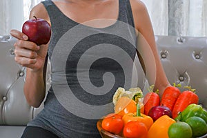 The healthy Asian pregnant young woman holds the apple with many kinds of fruit and vegetable