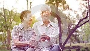 Healthy Asian senior couple drinking coffee in morning park together