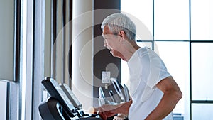 Healthy Asian senior couple exercise together in gym running treadmill