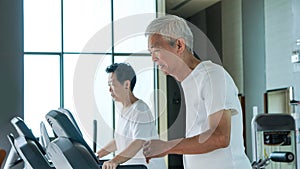 Healthy Asian senior couple exercise together in gym running treadmill