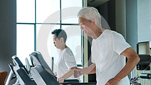 Healthy Asian senior couple exercise together in gym running treadmill