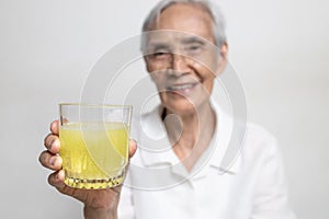 Healthy asian senior grandmother drinking a glass of vitamin C or orange juice,elderly people with effervescent vitamin C,