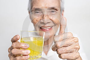 Healthy asian senior grandmother drinking a glass of vitamin C,orange juice,smiling elderly people with effervescent vitamin C,