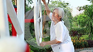 Healthy asian senior woman enjoying,exercising with exercise machine in a public park,female elderly performs physical work out on