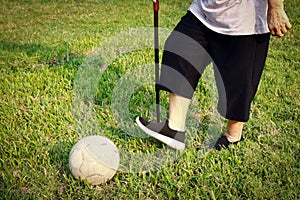 Healthy asian senior woman exercising with old soccer ball,active female elderly with walking stick, play game the football