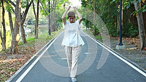 Healthy asian senior woman standing upright doing swinging their arms up and down while walking exercising outdoor on the street,f