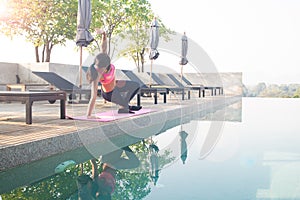 Healthy asian woman doing yoga and exercising near swimming pool. Healthy and wellbeing
