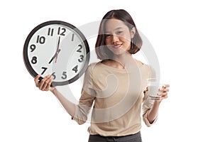 Healthy Asian woman drinking glass of milk hold clock