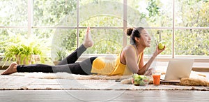 Healthy Asian woman lying on the floor eating salad looking relaxed and comfortable