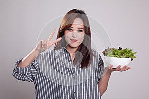 Healthy Asian woman show victory sign with salad.