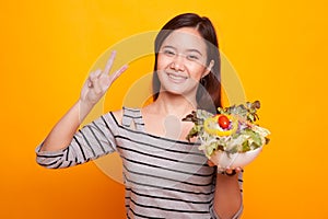 Healthy Asian woman show victory sign with salad.