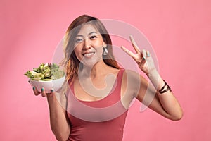 Healthy Asian woman show victory sign with salad