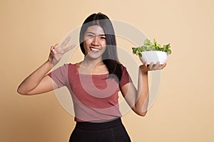 Healthy Asian woman show victory sign with salad