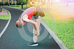 Healthy Asian woman stretching her legs before run in park. Fitness and exercise concept