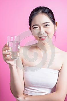 Healthy asian young beautiful woman drinking water, beauty face natural makeup, isolated over pink background.