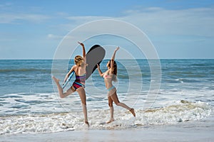 Healthy athletic surfer girl friends with fit bodies holding bodyboards