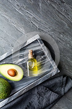 Healthy avocado oil in a glass bottle, decorated with sliced avocado with copy space