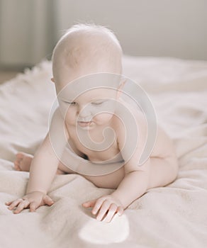 Healthy baby in bed.  Cute happy baby girl sitting and playing.  A portrait of a beautiful baby girl. Childhood, baby care concept