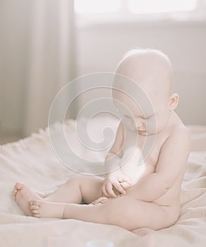 Healthy baby in bed.  Cute happy baby girl sitting and playing.  A portrait of a beautiful baby girl. Childhood, baby care concept