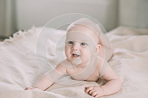 Healthy baby in bed.  Cute happy baby girl sitting and playing.  A portrait of a beautiful baby girl. Childhood, baby care concept