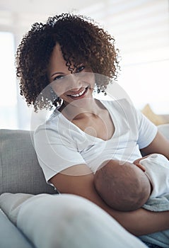 Healthy baby, happy mom. a young woman breastfeeding her adorable baby girl on the sofa at home.