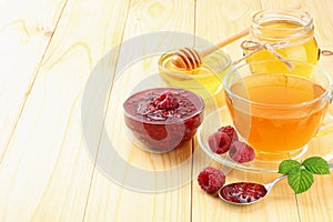 healthy background. raspberry with raspberry jam, honey and tea on light wooden background. top view with copy space