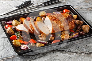 Healthy baked glazed pork loin with vegetables and mushrooms close-up on a baking sheet. Horizontal