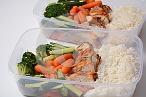 Healthy balanced lunch boxes. Grilled chicken, carrots, cucumbers, broccoli, and white rice.