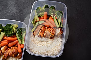 Healthy balanced lunch boxes. Grilled chicken, carrots, cucumbers, broccoli, and white rice.