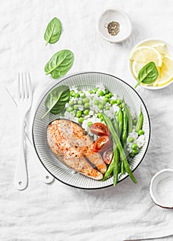 Healthy balanced meal lunch plate - baked salmon with rice and vegetables on a light background