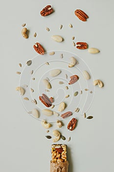 Healthy bar with nuts and seeds on the gray background, top view