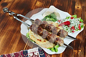 Healthy barbecued lean cubed pork kebabs served with a corn tortilla and fresh lettuce and tomato salad, close up view