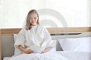 Healthy and beautiful girl reading book on bed with happy and beautiful face