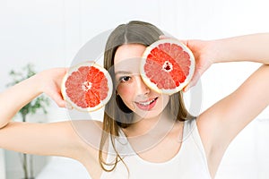 Healthy, beautiful smile, cute happy girl holding halves of grapefruit near face. Healthy food concept. Skin care and