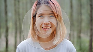 Healthy beautiful young Asian runner woman feeling happy smiling and looking to camera after running on forest trail. Lifestyle