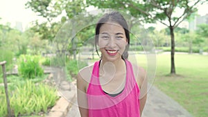 Healthy beautiful young Asian runner woman feeling happy smiling and looking to camera after running on street in urban city park.