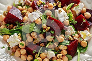 Healthy Beet Salad with chickpeas, pistachios nuts, feta cheese on rustic wooden background. close up