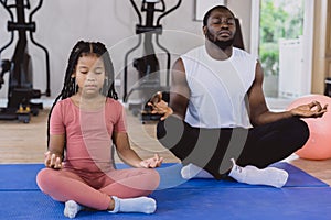 Healthy black family child and parent yoga concentration meditation vital fitness activity together at sport club