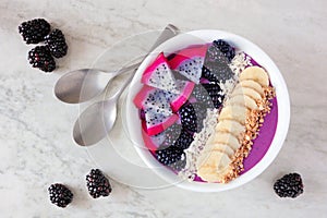 Healthy blackberry smoothie bowl, top view on a white marble background