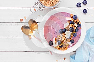Healthy blueberry and coconut smoothie bowl, table scene on white wood