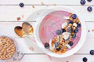 Healthy blueberry and coconut smoothie bowl, table scene on white wood