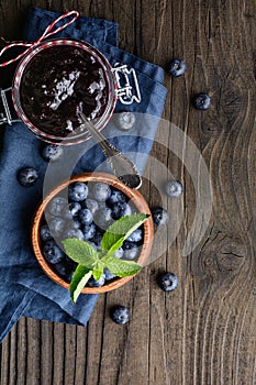 Healthy blueberry jam in a glass jar served with fresh berries with copy space
