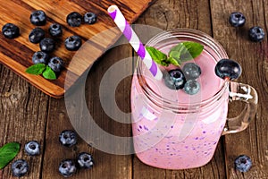 Healthy blueberry smoothie in a mason jar glass, downward view against rustic wood