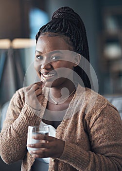 A healthy body is a healthy life. an attractive young woman sitting alone and taking her medication with water in her