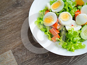 Healthy bowl of homemade salad with fresh vegetables, crab stick, eggs