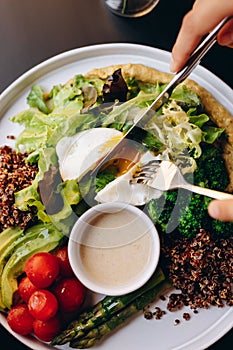 A healthy bowl of quinoa, poached egg, asparagus, tomatoes, chickpeas and avocado. Restaurant service