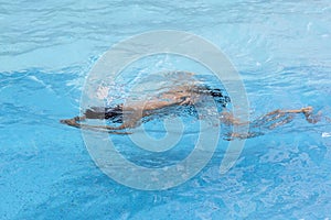 Healthy boy breast stroke swims in swimming pool